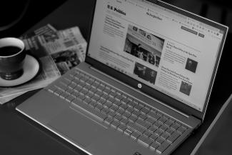 a laptop computer sitting on top of a desk next to a cup of coffee by Anna Keibalo courtesy of Unsplash.